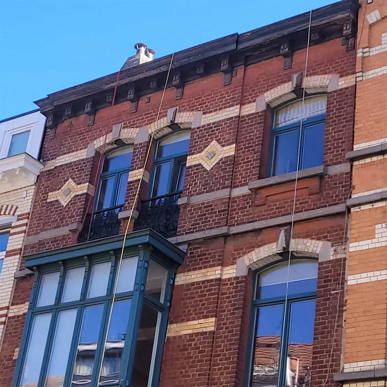Travaux en hauteur Bruxelles début cordes installées pour peinture corniche loggia châssis maison de maître en brique de Schaerbeek