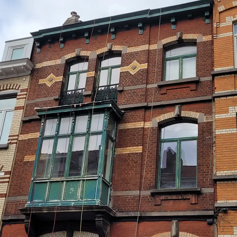 Travaux en hauteur Bruxelles en cours ponçage corniche loggia châssis maison de maître en brique de Schaerbeek