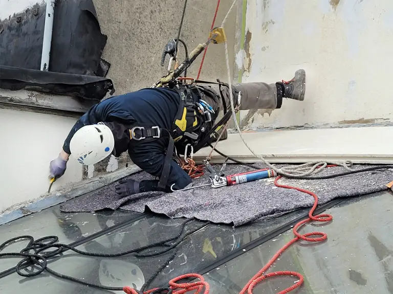 Cordiste de l'entreprise Hissé ô suspendu au dessus d'une verrière, réfection de joint silicone
